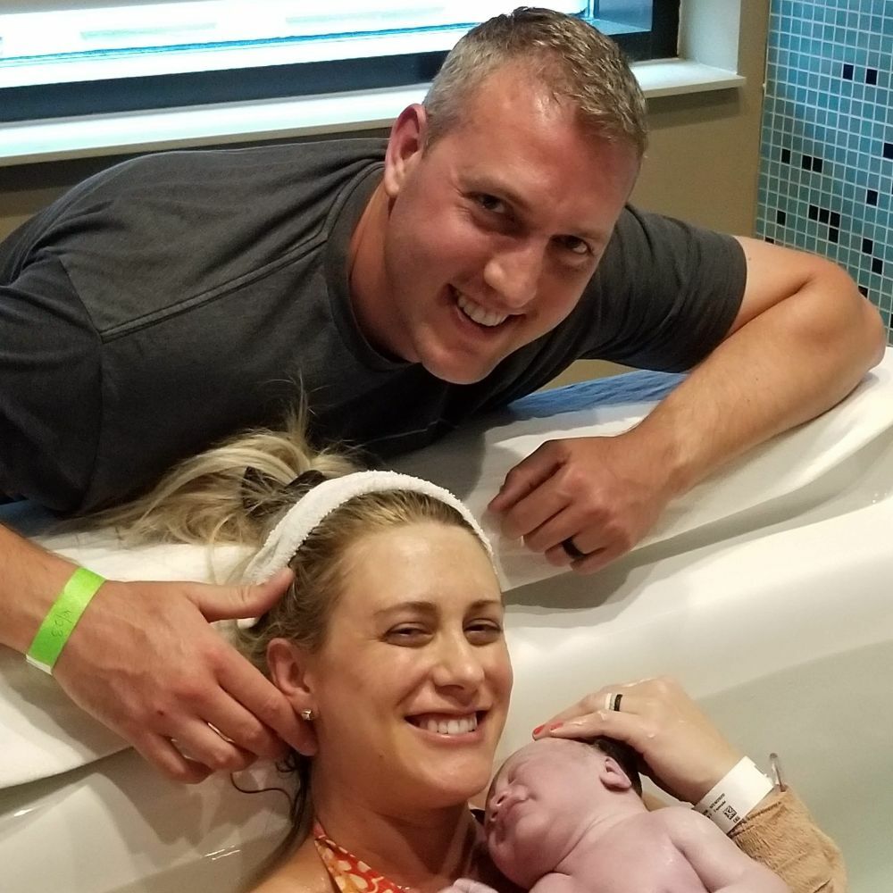 couple holding newborn baby in birthtub